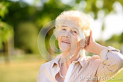 Outdoors portrait of beautiful smiling senior woman with curly white hair Stock Photo