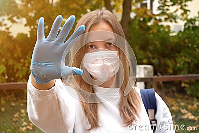Outdoors portrait of beautiful young woman wearing cotton white mask and medicalgloves greeting and say hello, Nature and trees in Stock Photo