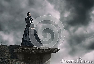 Outdoors portrait of a victorian lady in black standing on the cliff Stock Photo