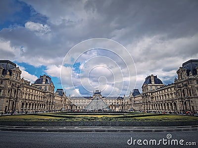 Outdoors view to the Louvre Museum in Paris, France. The historical palace building with the modern glass pyramid in center Editorial Stock Photo