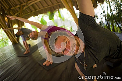 Outdoors yoga lesson - group of young people and coach woman practicing relaxation exercise at Asian wellness retreat hut training Stock Photo