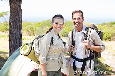 Outdoorsy couple smiling at camera outside their tent Stock Photo