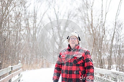 Outdoorsy man in plaid walking over bridge during snowfall Stock Photo