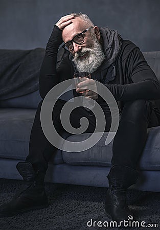 Outgoing pensioner drinking liquid on sofa Stock Photo