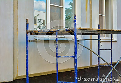 Outside repair, renovation of apartment house, blue paint metal scaffold tower Stock Photo