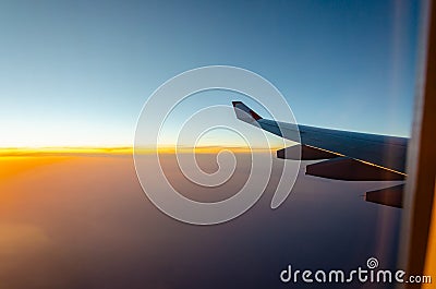 Outside the window`s airplan sunset seen with aircraft wing. Stock Photo