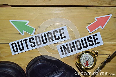 Outsource or Inhouse opposite direction signs with boots,eyeglasses and compass on wooden Stock Photo