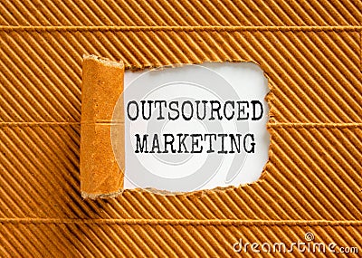 Outsourced marketing symbol. Concept words Outsourced marketing on beautiful white paper. Beautiful brown paper background. Stock Photo