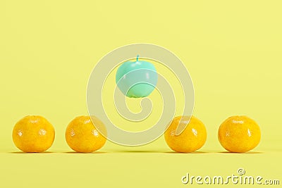 Outstanding blue painted apple floating among real oranges on pastel yellow background Stock Photo