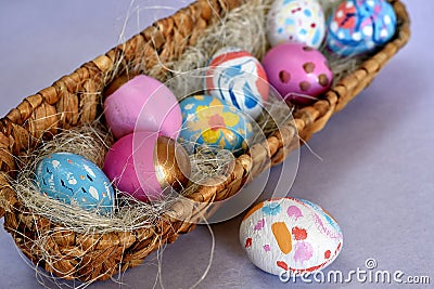Oval basket full of brightly colored Easter eggs with one white spotted egg beside Stock Photo