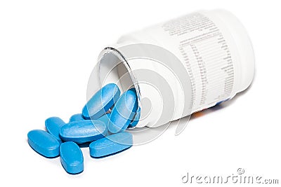 Oval blue pills spill from white prescription bottle Stock Photo