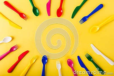 Oval frame made of reusable cutlery on the yellow background. Plastic spoons, forks, knives top view. Summer Picnic Stock Photo