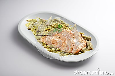 Oval plate with salmon fillet and artichoke garnish Stock Photo