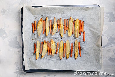 Oven baked carrot and potato with spices and herbs on baking tray. Grilled vegetables Stock Photo