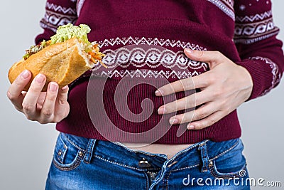 Over eating on holidays concept. Cropped close up photo of satisfied but feeling not perfect in abdomen girl holding large dish Stock Photo