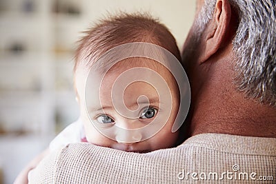 Over shoulder close up of grandfather holding his baby grandson, baby looking to camera Stock Photo