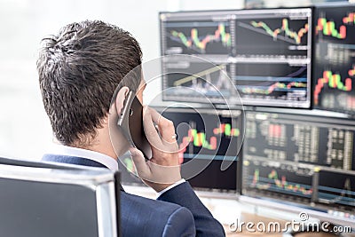 Over the shoulder view of computer screens and stock broker trading online. Stock Photo