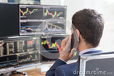 Over the shoulder view of computer screens and stock broker trading online. Stock Photo