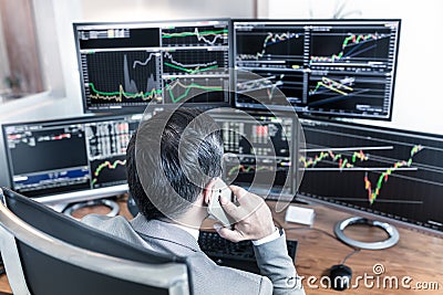 Over the shoulder view of computer screens and stock broker trading online. Stock Photo