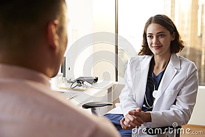 Over The Shoulder View Of Man Having Consultation With Female Doctor In Hospital Office Stock Photo