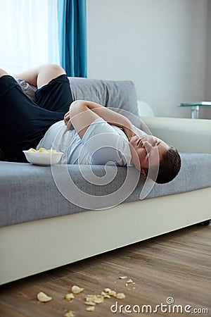 Overeat fat boy sleep on sofa in living room Stock Photo