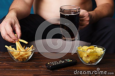 Overeating man sitting on the sofa with tv remote Stock Photo