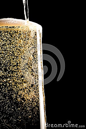 Overflow pouring champagne in the flute with golden bubbles Stock Photo