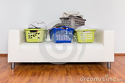 Overflowing laundry baskets full of dirty clothes on sofa Stock Photo