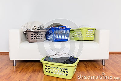 Overflowing laundry baskets full of dirty clothes on sofa Stock Photo