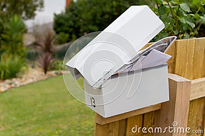 Overflowing letterbox on fence post Stock Photo