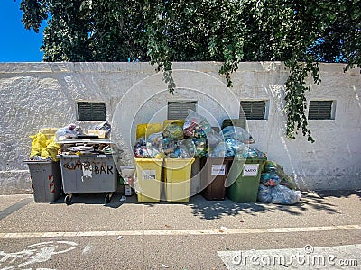 Overflowing public trash containers in the streets of Alghero, Italy Editorial Stock Photo