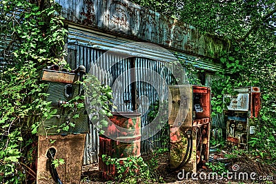Overgrown Abandoned Garage with Derelict Gas Pumps Stock Photo