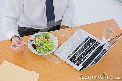 Overhead of a businessman eating a salad on his desk Stock Photo