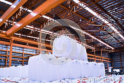 Overhead crane lift jumbo bags of tapioca using spread bar in storage warehouse. Bulk cargo in jumbo bag handling equipmet. Stock Photo