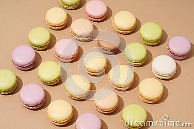 overhead shot of a beige table surface featuring an array of colorful macarons in neat rows Stock Photo