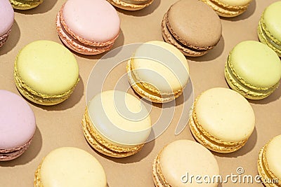 overhead shot of a beige table surface featuring an array of colorful macarons in neat rows Stock Photo