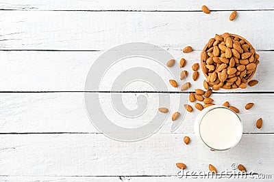 Overhead shot of glass of almond milk on white wooden background with almonds in bowl and copyspace Stock Photo