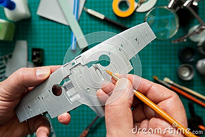 Overhead View Of Man Building Scale Model Aeroplane From Kit On Cutting BoardWith Tools And Materials Stock Photo