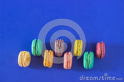 Overhead shot of rows of colorful macarons on a blue background Stock Photo