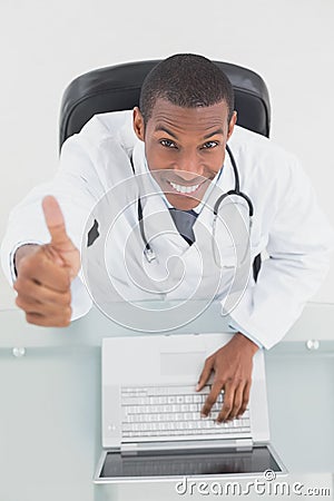 Overhead of smiling male doctor with laptop gesturing thumbs up Stock Photo