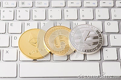 Overhead top close up view photo of silver litecoin golden ethereum and bitcoin laying on computer white keyboard background Editorial Stock Photo