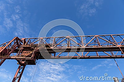 Overhead trusses, catwalks, and stairs of a massive industrial structure against a deep blue sky Stock Photo