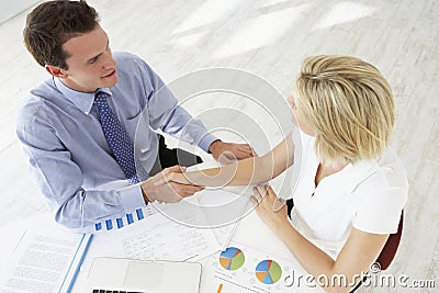 Overhead View Of Businesswoman And Businessman Working At Desk Together Shaking Hands Stock Photo