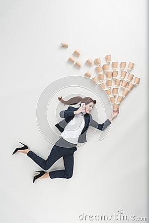 overhead view of businesswoman with disposable cups talking on smartphone Stock Photo