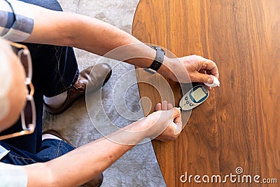 Overhead view of caucasian senior man measuring his blood sugar using glucometer at home Stock Photo