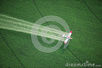 A crop duster spraying a green farm field. Stock Photo