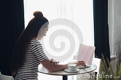 Overhead view of an executive woman typing in her laptop. View from the back of a female sitting at the table with a cup Stock Photo