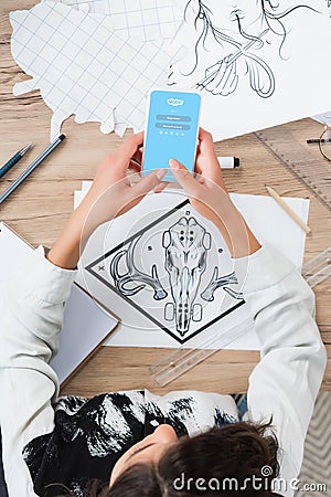 overhead view of female designer using smartphone with skype application on screen at working table Editorial Stock Photo