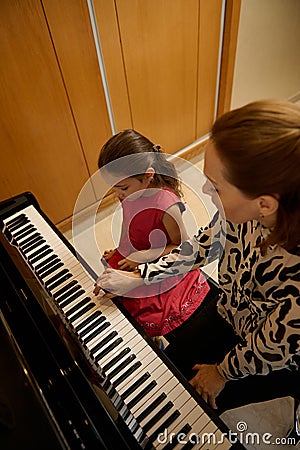 Overhead view of a female pianist musician holding the hands of a little child girl, showing the true position of finger Stock Photo