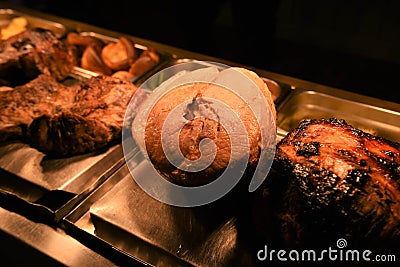 Whole cooked roast joints of gammon pork and lamb taken in a restaurant Stock Photo